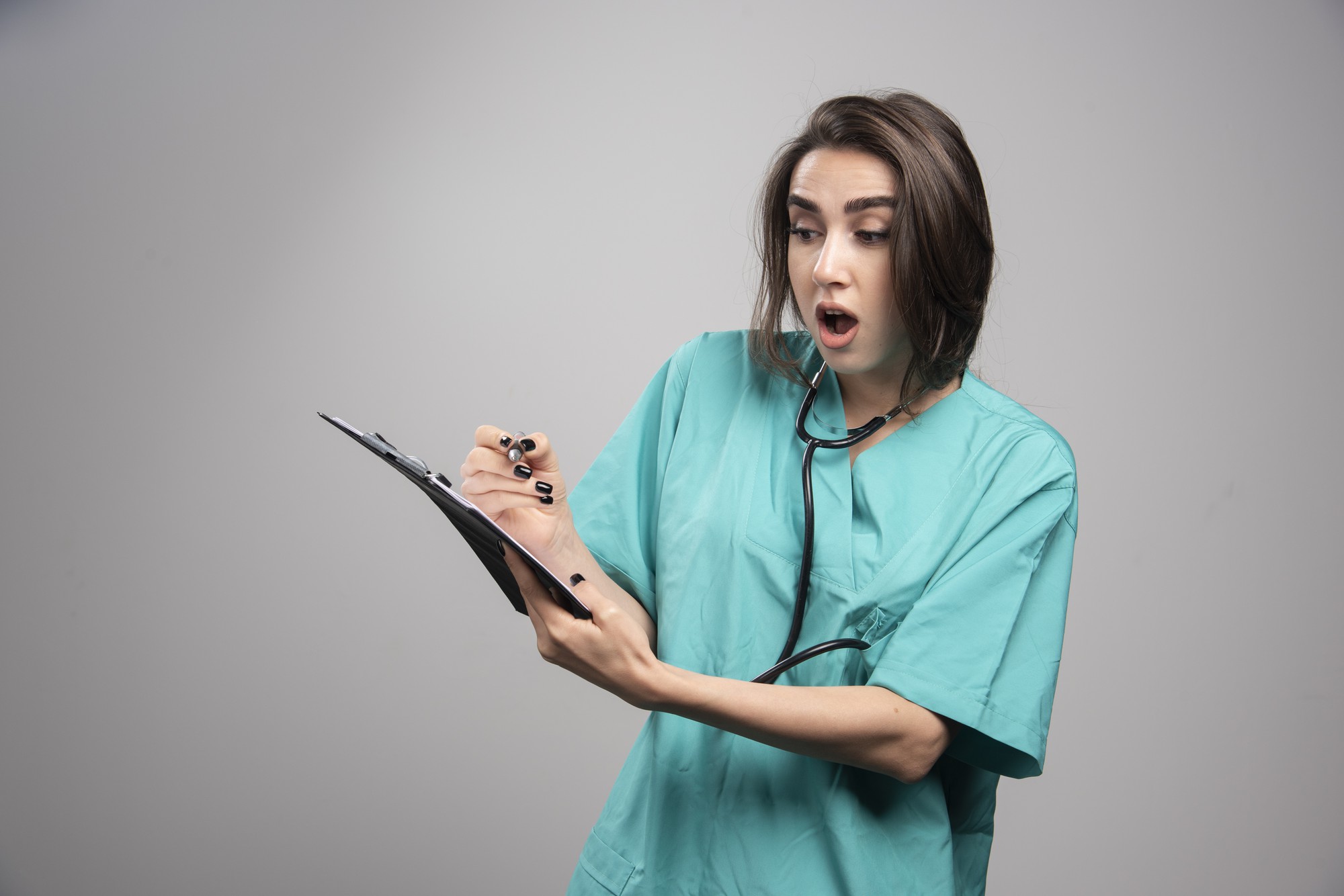 Médecin surpris en uniforme bleu debout sur fond gris. Photo de haute qualité