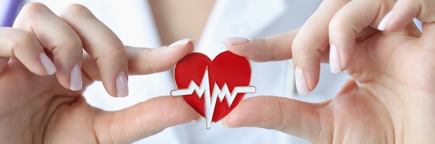 Le médecin tient dans ses mains une icône avec un cardiogramme du concept de maladie cardiaque et vasculaire