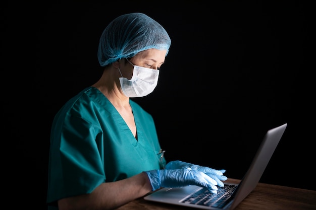 Médecin de tir moyen avec ordinateur portable et masque