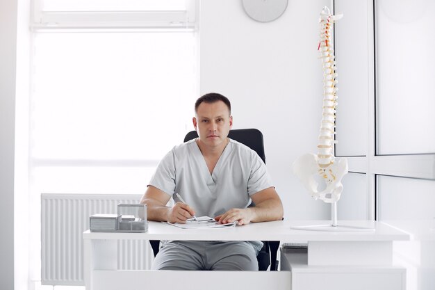 Médecin en uniforme blanc au bureau