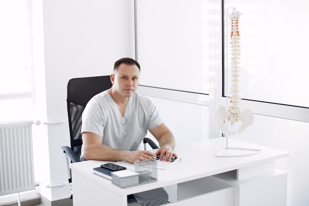 Médecin en uniforme blanc au bureau