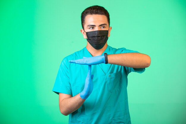 Médecin en uniforme vert et masque facial faisant des gestes pour faire comprendre les gens.