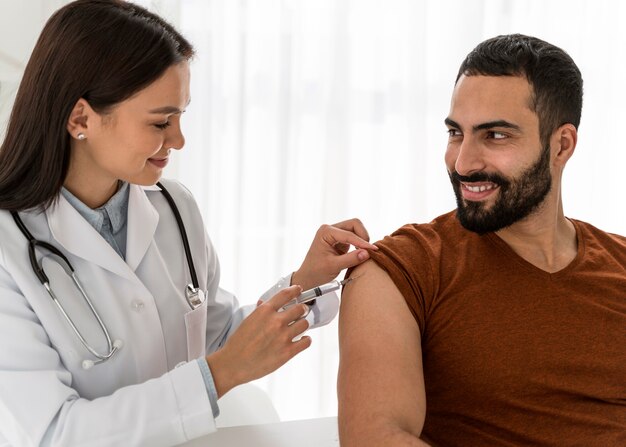 Médecin vaccinant un bel homme