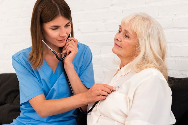 Médecin vérifiant une vieille femme avec son stéthoscope