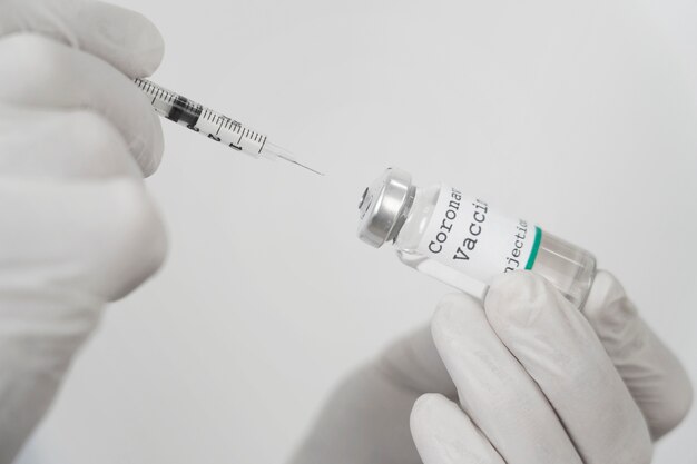 Medic avec des gants en latex tenant un flacon de vaccin et une seringue