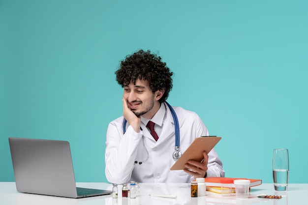 Medical mignon beau médecin travaillant sur ordinateur à distance en blouse de laboratoire regardant dans la caméra