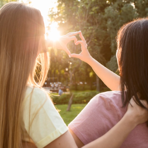 Photo gratuite meilleurs amis faisant un cœur au soleil