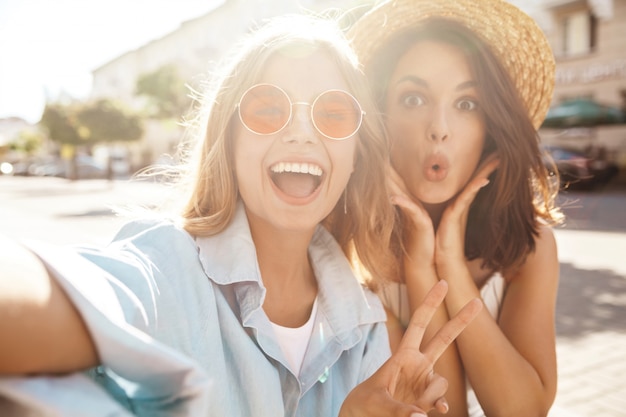 Meilleurs amis portant une tenue élégante et prenant selfie dans la rue