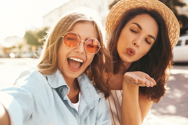 Meilleurs amis portant une tenue élégante et prenant selfie dans la rue