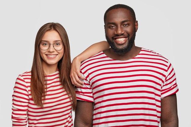 Meilleurs amis positifs posant contre le mur blanc