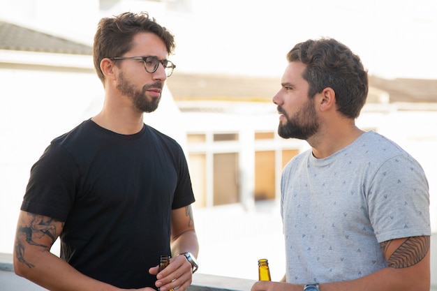 Photo gratuite les meilleurs amis de sexe masculin discutant des problèmes autour d'une bouteille de bière