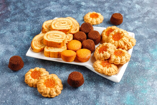 Photo gratuite mélange de biscuits sucrés, cake roll, mini cupcakes.