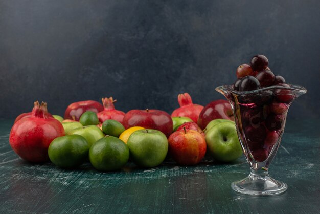 Mélange de fruits frais et verre de raisin noir sur table en marbre.