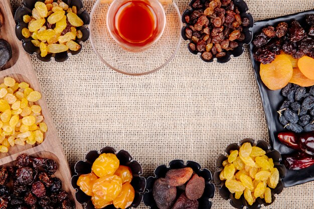 Mélange de fruits secs dattes raisins secs abricots et cerises en mini tartelettes servies avec du thé sur un sac avec copie espace vue de dessus