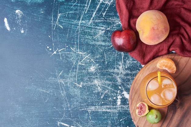 Mélange de fruits avec une tasse de boisson sur bleu.