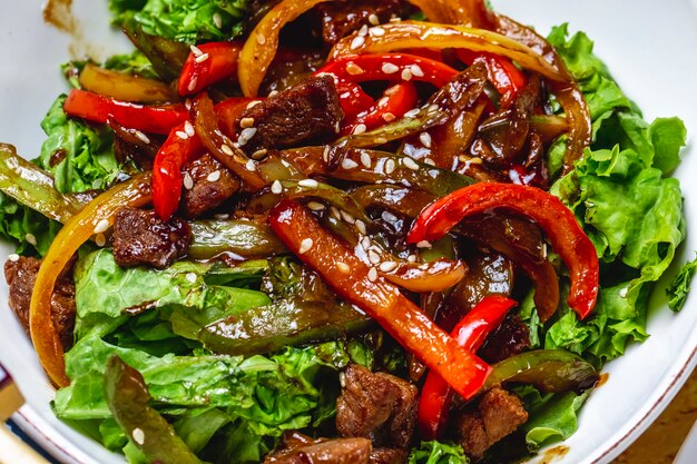 Mélange de salade de viande poivrons laitue sauce sésame barbecue vue latérale