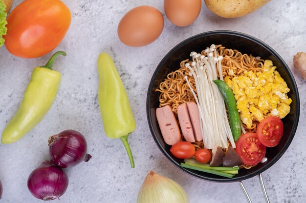 Mélanger les nouilles frites qui combinent le maïs, le champignon doré, la tomate, la saucisse, l'edamame et les oignons nouveaux dans une poêle.