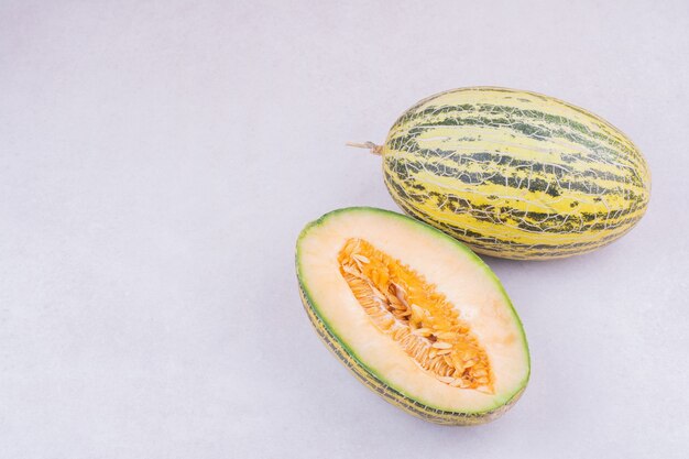 Melon entier et demi coupé en surface grise