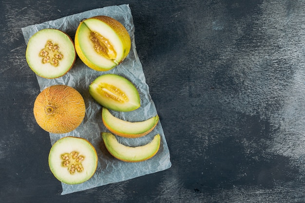 Melon en tranches sur un fond de tissu en bois foncé et gris. vue de dessus. espace pour le texte