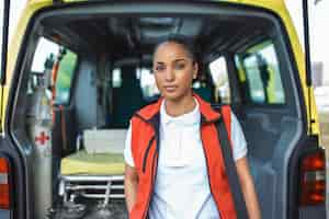 Photo gratuite un membre du personnel ambulancier sort de l'arrière d'une ambulance avec son sac à dos d'urgence et son moniteur de signes vitaux