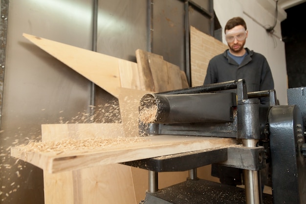 Photo gratuite menuisier de charpentier travaillant sur une clochette électrique avec des planches en bois