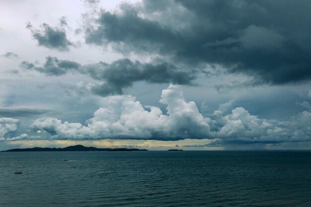 Mer avec des bateaux au loin sous un ciel nuageux