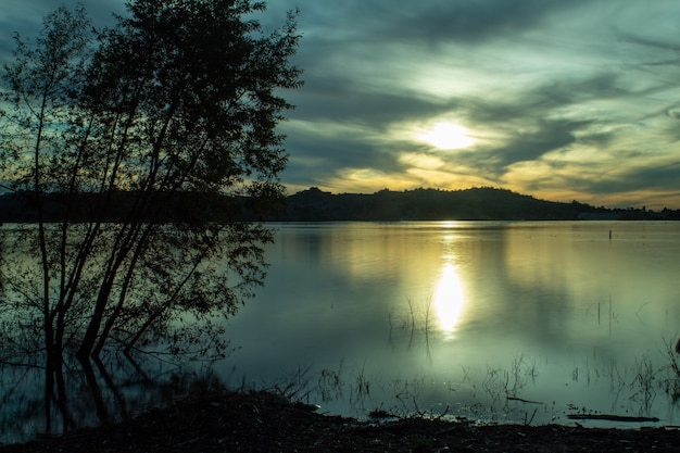 Mer entourée de collines sous le soleil et un ciel nuageux le soir