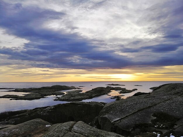 Mer entourée de rochers sous un ciel nuageux pendant le coucher du soleil à Rakke en Norvège