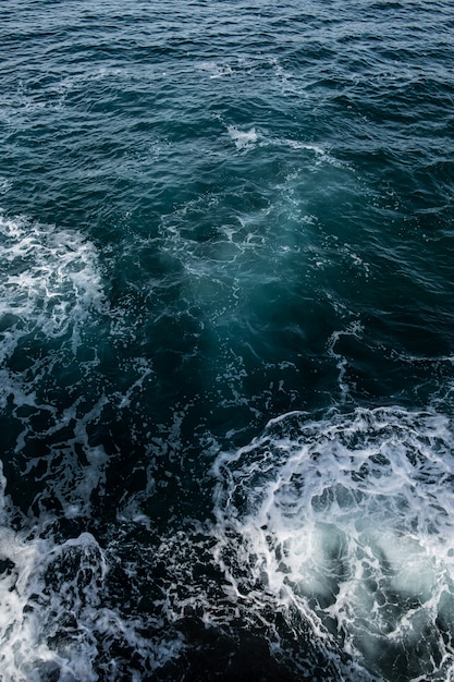 Mer orageuse, surface de l'eau d'un bleu profond avec de la mousse et des vagues
