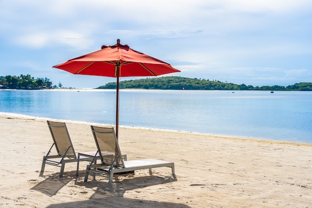 Mer tropicale en plein air de plage tropicale avec chaise de parasol et terrasse de salon autour de là sur le ciel bleu de nuage blanc