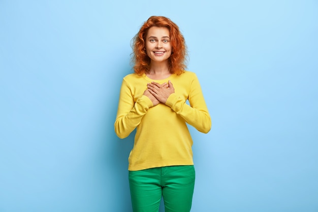 Merci pour le soutien. Superbe femme rousse se sent touchée et reconnaissante appuie ses mains sur la poitrine, apprécie l'aide