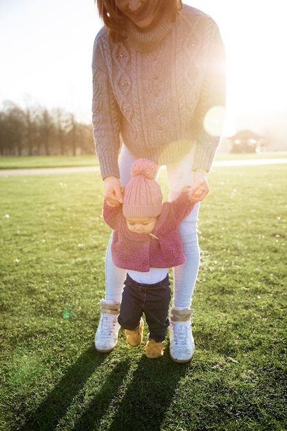 Photo gratuite mère aidant un enfant à marcher dans le parc