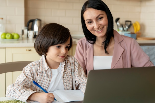 Mère aidant son fils dans une classe en ligne