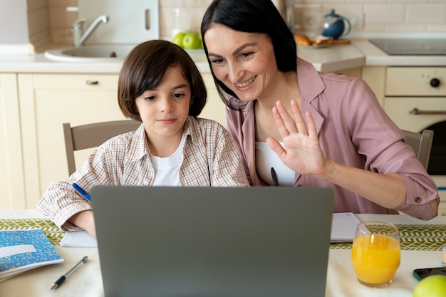 Mère aidant son fils dans une classe en ligne