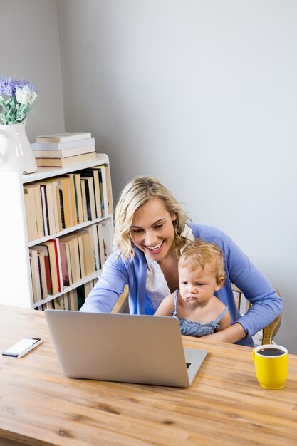 Mère et bébé assis à table et utilisant un ordinateur portable