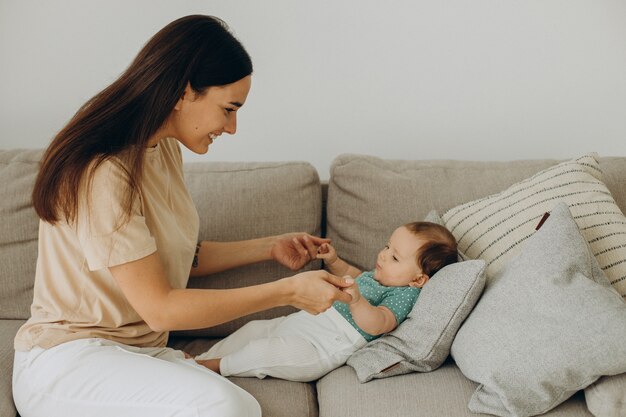 Mère avec bébé fille sur canapé à la maison