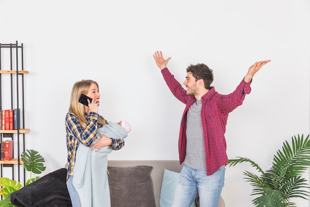 Mère avec bébé parle au téléphone près de père heureux