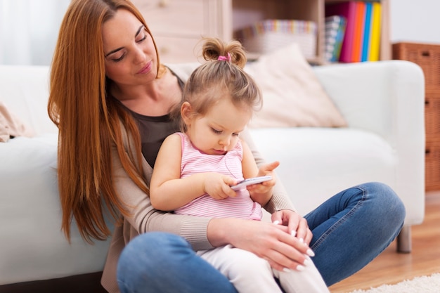 Mère et bébé avec téléphone portable à la maison