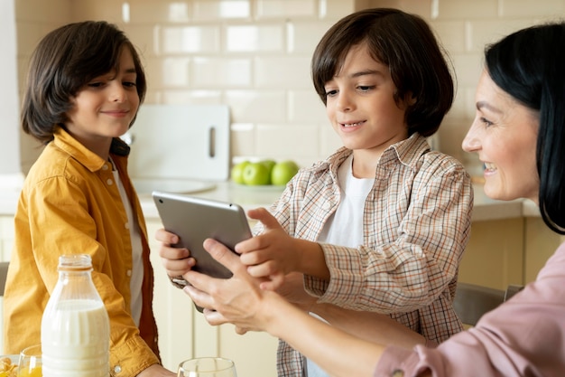 Photo gratuite mère donnant une tablette à ses jumeaux