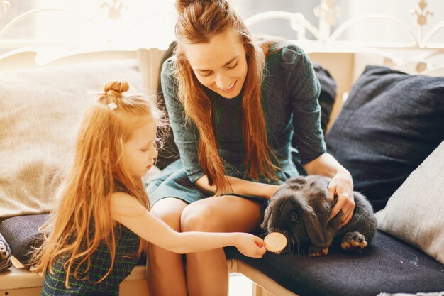 mère élégante avec de longs cheveux et une robe verte jouant avec sa petite fille mignonne