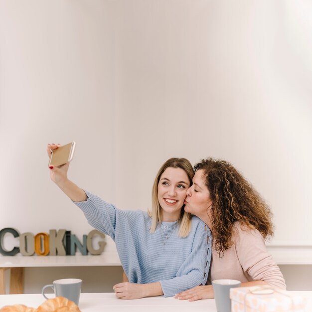 Mère embrassant la fille tout en posant por selfie