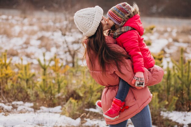 Mère embrassant la petite fille dans une forêt d'hiver