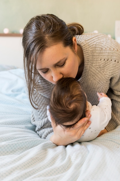 Photo gratuite mère embrasse bébé dans bras