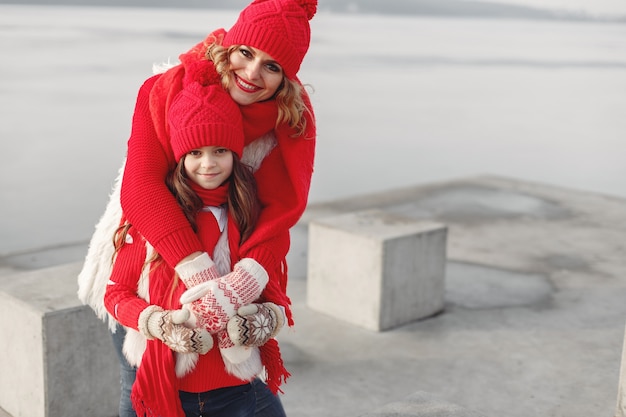 Mère et enfant en chapeaux d'hiver tricotés en vacances de Noël en famille. Bonnet et écharpe en laine faits à la main pour maman et enfant. Tricoter pour les enfants. Vêtements d'extérieur en tricot. Femme et petite fille dans un parc.