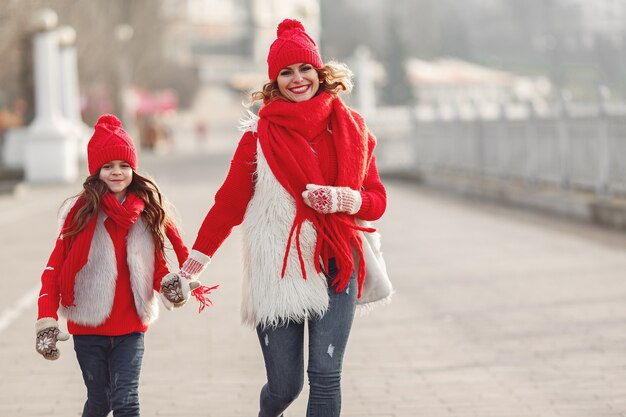 Mère et enfant en chapeaux d'hiver tricotés en vacances de Noël en famille. Bonnet et écharpe en laine faits à la main pour maman et enfant. Tricoter pour les enfants. Vêtements d'extérieur en tricot. Femme et petite fille dans un parc.