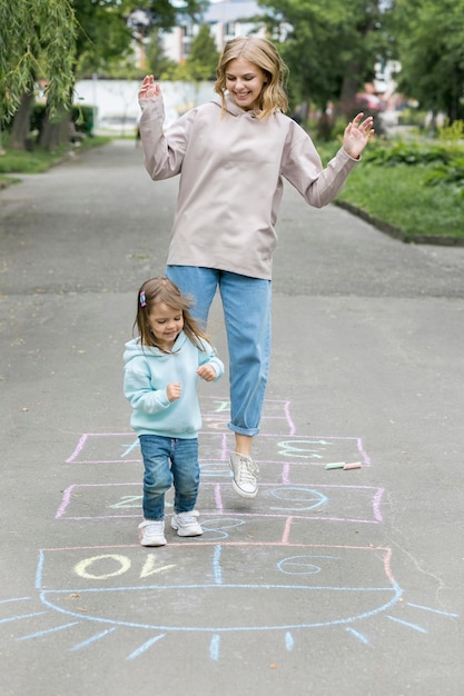 Mère et enfant mignon jouant à la marelle