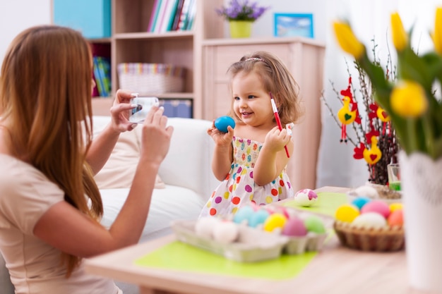 Mère fière de prendre une photo de sa fille avec un œuf de Pâques