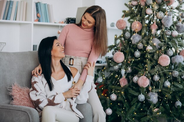 Mère avec fille adulte avec des cadeaux de Noël par l'arbre de Noël