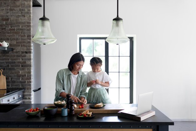 Mère et fille ayant un appel vidéo depuis leur cuisine