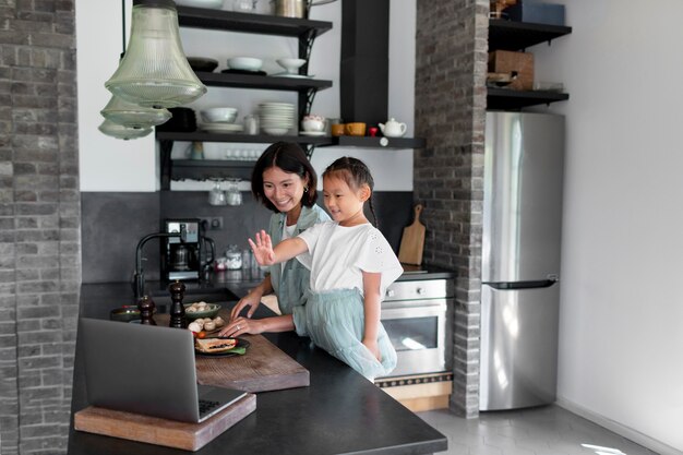 Mère et fille ayant un appel vidéo depuis leur cuisine